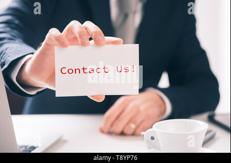 CONTACT US message on the card shown by a businessman  close up Stock Photo