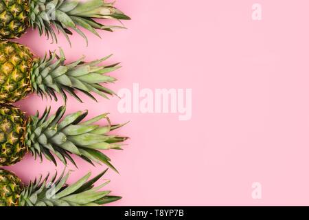 Pineapple fruit side border on a pastel pink background. Top view, flat lay with copy space. Stock Photo