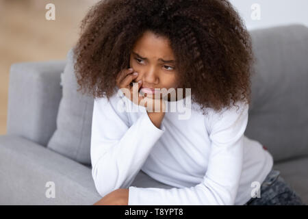 Close up upset African American teenage girl sitting alone Stock Photo