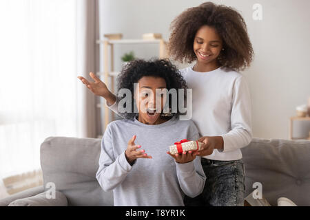 Surprised African American mother receiving gift from teenage daughter Stock Photo