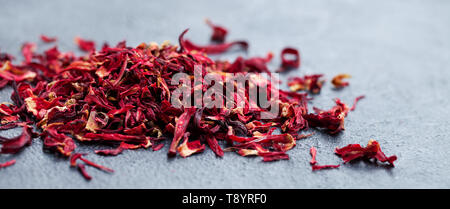 Hibiscus flower tea scattered on grey stone background. Copy space. Stock Photo