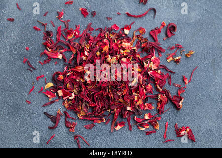 Hibiscus flower tea scattered on grey stone background. Copy space. Top view. Stock Photo