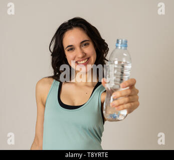 Portrait of beautiful fitness athlete Young latin Woman holding water bottle after work out exercising isolated on grey background in drinking water b Stock Photo