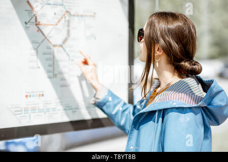 Woman looking on the scheme of public transport while standing at the tram station outdoors Stock Photo