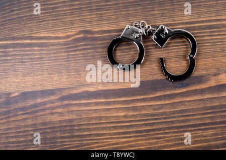 Handcuffs on a dark wood background Stock Photo