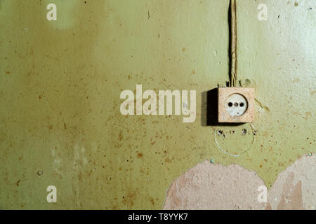 Old power socket isolated on damaged green wall - reconstruction background Stock Photo