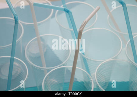 Plastic cups with white and blue straw tubules. Concept of plastic things in everyday life. Selective focus, top view Stock Photo