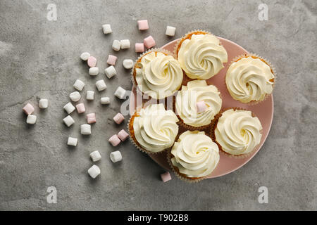 Plate with sweet cupcakes and marshmallows on grey table Stock Photo