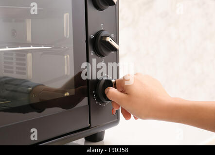 Woman adjusting electric oven in kitchen Stock Photo