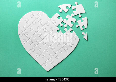 Heart-shaped jigsaw puzzle on color background Stock Photo