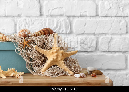 Starfish, seashells and pebbles as decorations on table near white brick wall Stock Photo