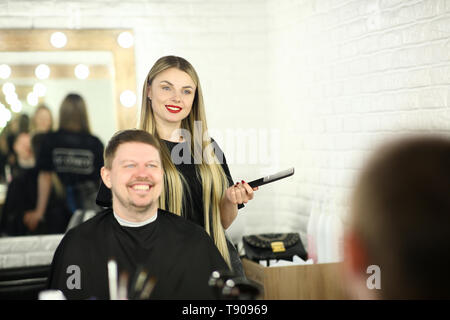 Young Hairdresser with Man Client in Beauty Salon Stock Photo