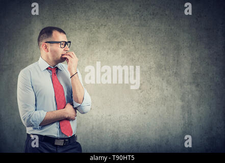 Business man in glasses biting nails being in panic and anxiety looking to the side feeling nervous Stock Photo