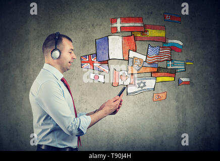 Business man in headphones using mobile phone app learning different languages Stock Photo