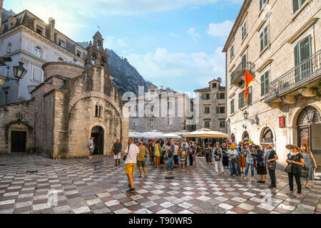 Tourists gather on St Luke's square in front of the old church with it's three bell towers in Kotor, Montenegro. Stock Photo