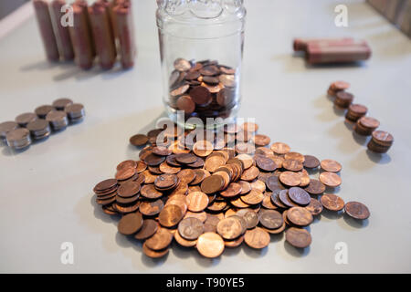 Counting pennies and coin money from spare change savings. Stock Photo
