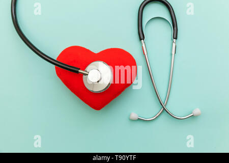 Simply minimal design with medicine equipment stethoscope or phonendoscope and red heart isolated on trendy pastel blue background. Instrument device  Stock Photo