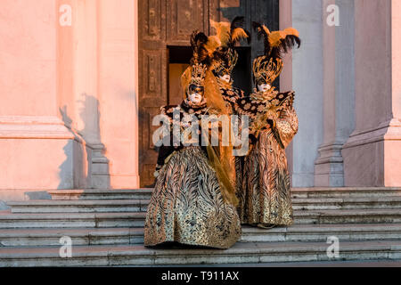 A masked couple in a beautiful creative costumes, posing on the island San Giorgio di Maggiore, celebrating the Venetian Carnival Stock Photo