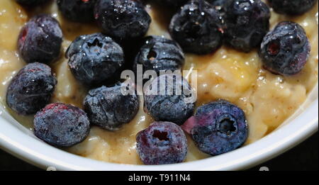 Bowl of oatmeal with frozen blueberries and a drizzle of honey Stock Photo