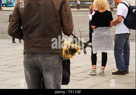 Illegal street vendor taking inventory of his merchandise while looking on at tourists Stock Photo