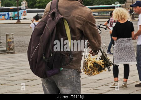 Illegal street vendor taking inventory of his merchandise while looking on at tourists Stock Photo