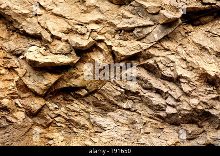 Background texture wallpaper of light brown to yellow stone formation mixed with wet dirt on warm sunny spring day Stock Photo