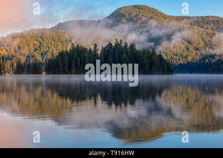 The morning sun illuminates the far shore of Main Lake, in Main Lake Provincial Park on Quadra Island, British Columbia, Canada. Stock Photo