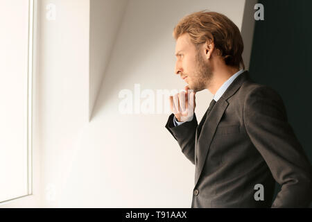 Thoughtful young businessman looking through window Stock Photo