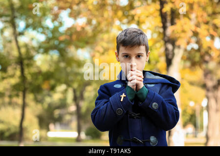 Little boy praying in park Stock Photo