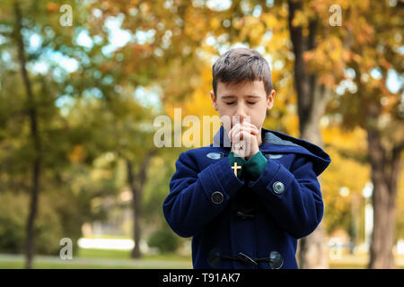 Little boy praying in park Stock Photo