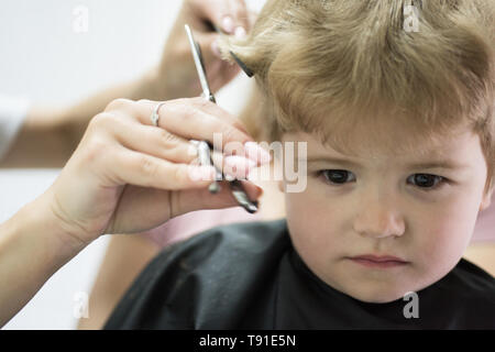 Hairdresser Cutting Hair Of Child In Front Of Tv Stock Photo