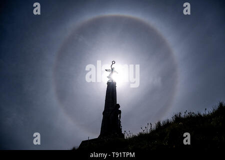 Aberystwyth Wales UK, Thursday 16 May 2019  UK Weather: A perfect circular sun halo , formed as the rays of the sun shine through ice crystals in the upper atmosphere, seen in the sky above the silhouette of the war memorial Aberystwyth. The halos, always at 22º from the sun,  often  indicate that rain will fall within the next 24 hours, since the cirrostratus clouds that cause them can signify an approaching frontal system. The  weather is set to change overnight from the fine warm conditions to cooler and wetter days, more typical of mid May.  photo credit Keith Morris / Alamy Live News Stock Photo