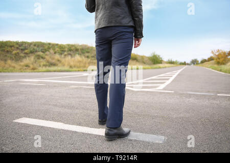 Young man standing at crossroads. Concept of choice Stock Photo