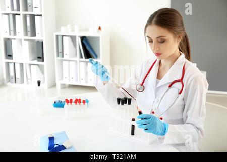 Female doctor dripping blood into test tube in laboratory Stock Photo