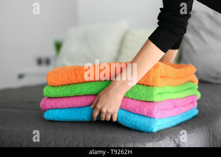 Woman putting stack of clean towels on bed Stock Photo