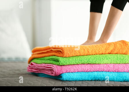 Woman putting stack of clean towels on bed Stock Photo
