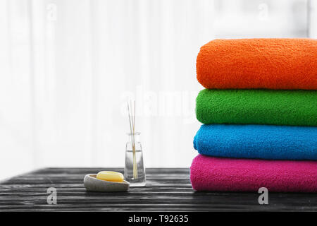 Folded bright terry towels and soap on wooden table Stock Photo