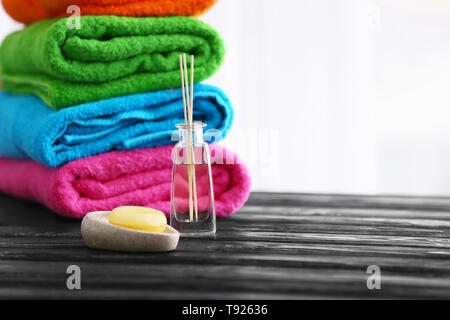 Soap and folded bright terry towels on wooden table Stock Photo
