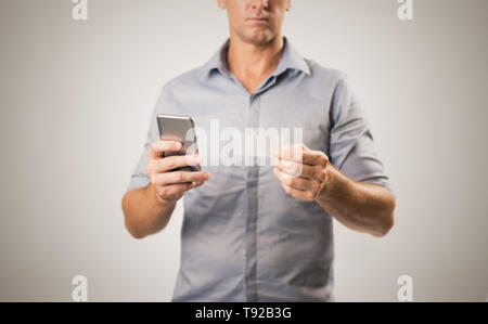 Young casual business man holding phone and business card possibly making contact - modern  business concept image over white background with copy spa Stock Photo