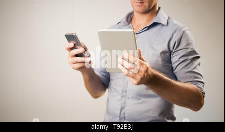 Man dressed casually in collared shirt using a tablet and phone -  Casual business concept image with copy space for text. Stock Photo