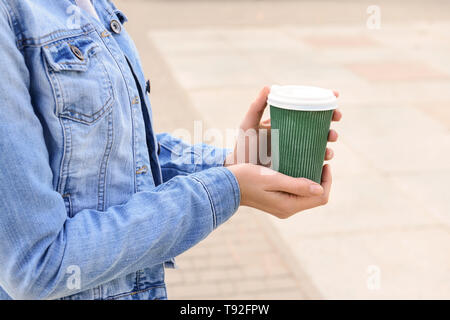 Woman holding paper coffee cup outdoors Stock Photo