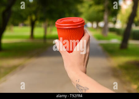 Woman holding paper coffee cup in park Stock Photo