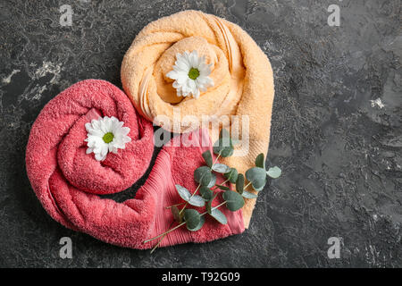 Heart made of rolled clean towels with flowers and eucalyptus branches on grey textured background, top view Stock Photo
