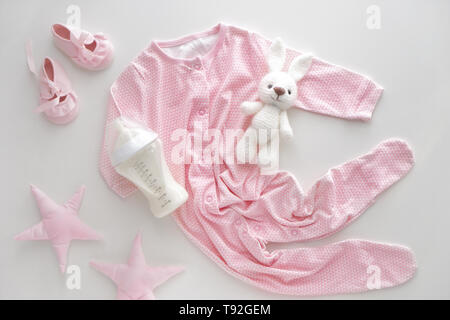 Feeding bottle of baby formula with toys and clothes on white background Stock Photo