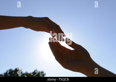 Male and female hands reaching out to each other outdoors Stock Photo