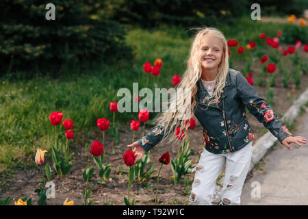 portrait of a beautiful little child girl with tulip flowers on a sunny spring day Stock Photo