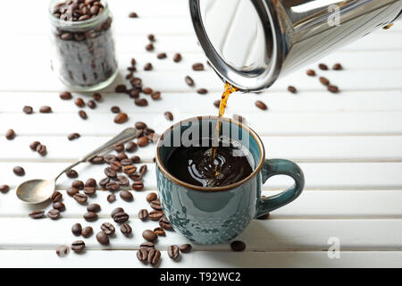 Pouring of hot coffee from Moka pot into cup on table Stock Photo