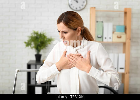 Woman having panic attack at workplace Stock Photo