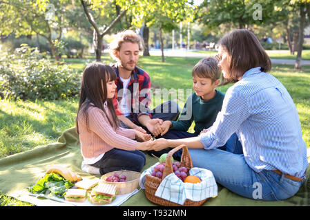 Family praying before meal in park Stock Photo