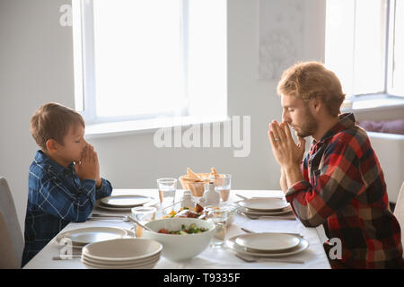 Father with son praying before meal at home Stock Photo